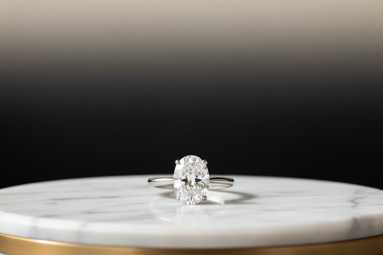 Oval cut diamond solitaire engagement ring in 18K white gold on marble — JewelryRich