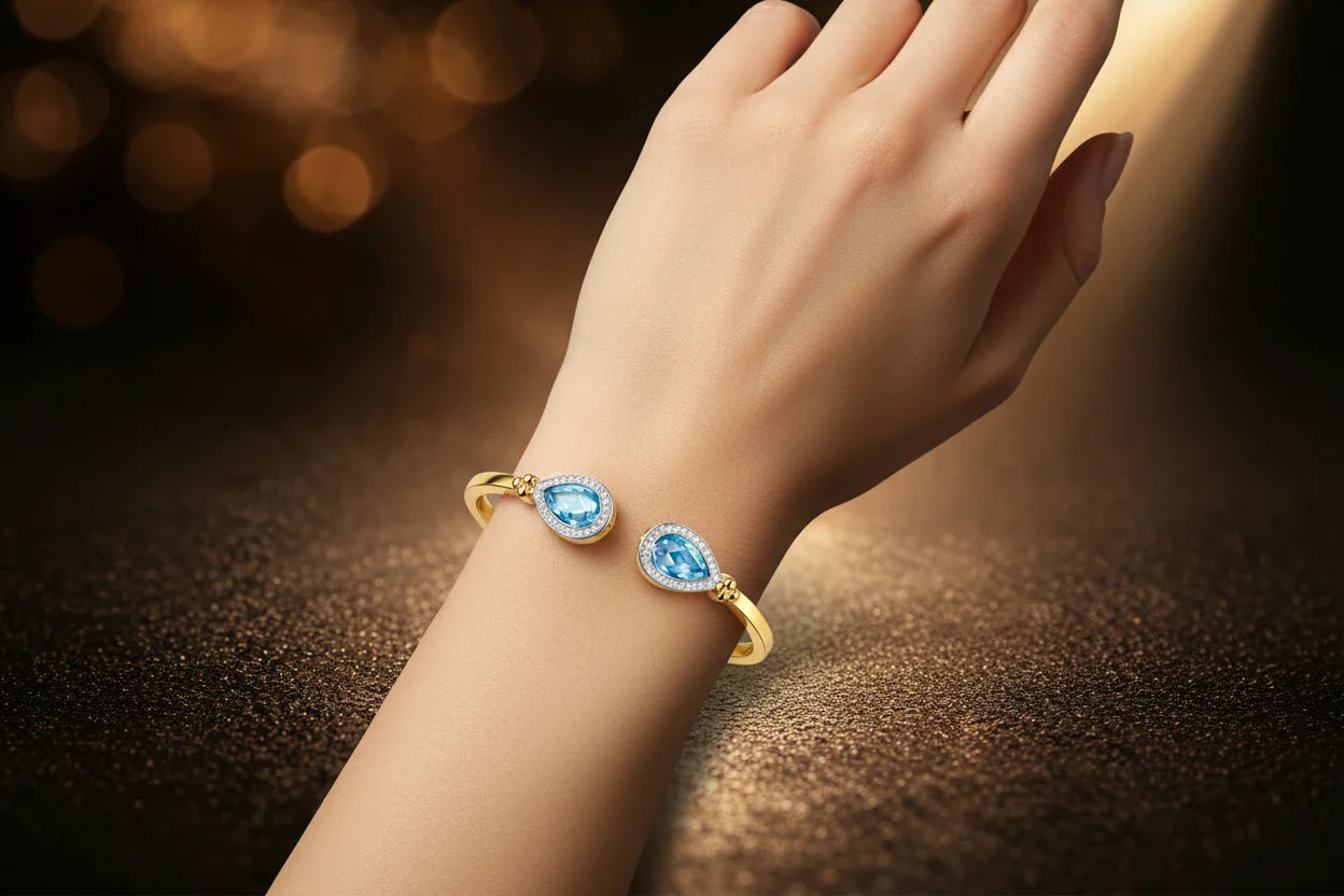 JewelryRich cuff bracelets collection — Teardrop Duet Swiss blue topaz and diamond 18K gold bangle worn on wrist
