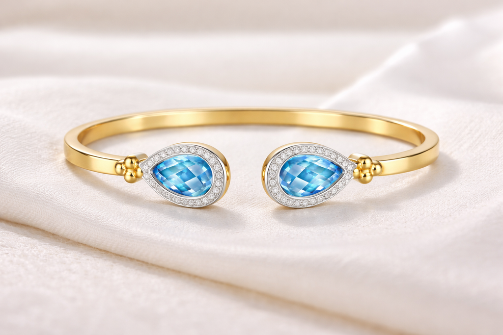 Teardrop Duet Cuff 18K Yellow Gold Swiss Blue Topaz diamond cuff bracelet – flat lay on fabric