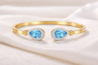 Teardrop Duet Cuff 18K Yellow Gold Swiss Blue Topaz diamond cuff bracelet – flat lay on fabric