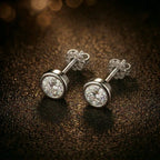 Single bezel-set diamond stud earring in 18K white gold on dark background, detail shot