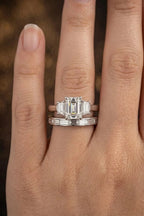 Emerald-cut three-stone diamond engagement ring stacked with baguette diamond wedding band, worn on hand, JewelryRich