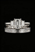 Emerald-cut three-stone diamond engagement ring with channel-set baguette wedding band, black background product shot, 18K White Gold, GIA certified, JewelryRich
