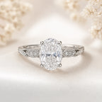 Close-up of oval brilliant cut diamond hidden halo engagement ring with vintage milgrain scrollwork band in platinum 950
