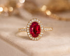 Close-up of oval ruby diamond halo ring in 18K yellow gold – vivid red gemstone with pavé setting | JewelryRich