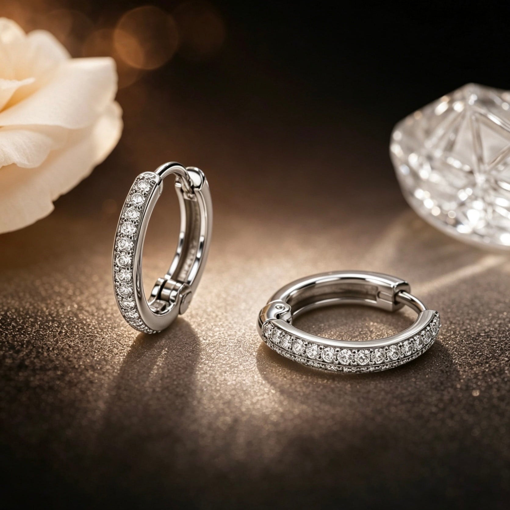 Pavé huggie clip-on earrings in 14K white gold photographed on dark editorial background with diamond bokeh, showcasing continuous sparkle and quiet luxury aesthetic