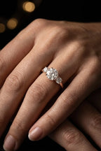 Three stone diamond engagement ring in 18K rose gold worn on hand — round brilliant center diamond with matching side stones | JewelryRich